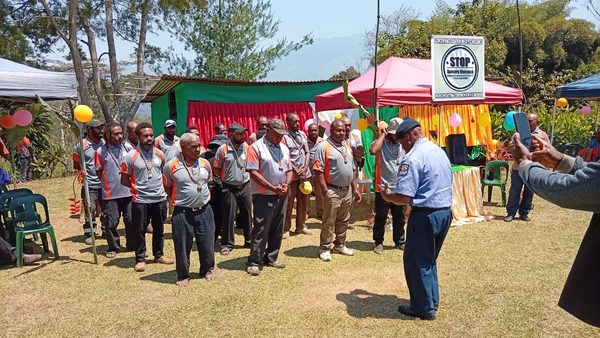 Facilitators gathered before the graduation banner. Foursquare Gospel Church, Lower Asaro, Eastern Highlands. August 2026.